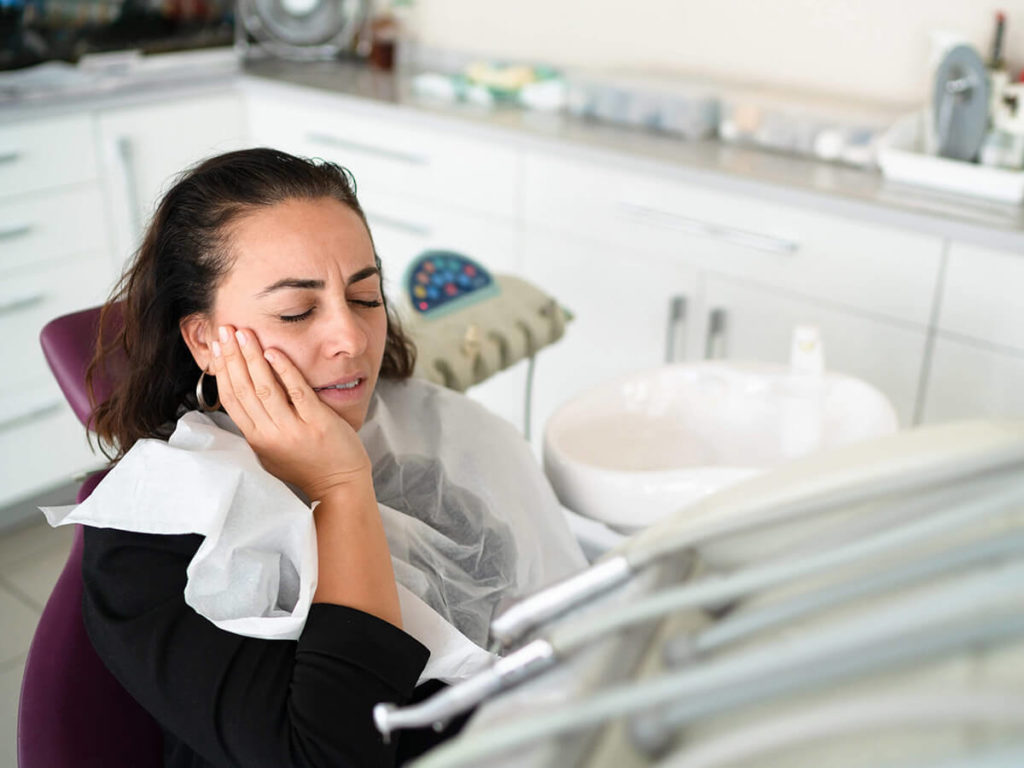 dental patient holding their face in pain