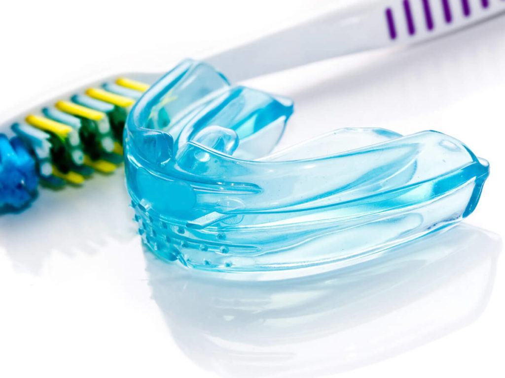 blue mouth guard sitting next to a tooth brush