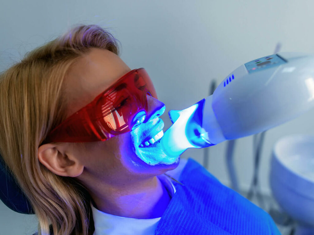 patient wearing protective glasses receiving teeth whitening via bright light