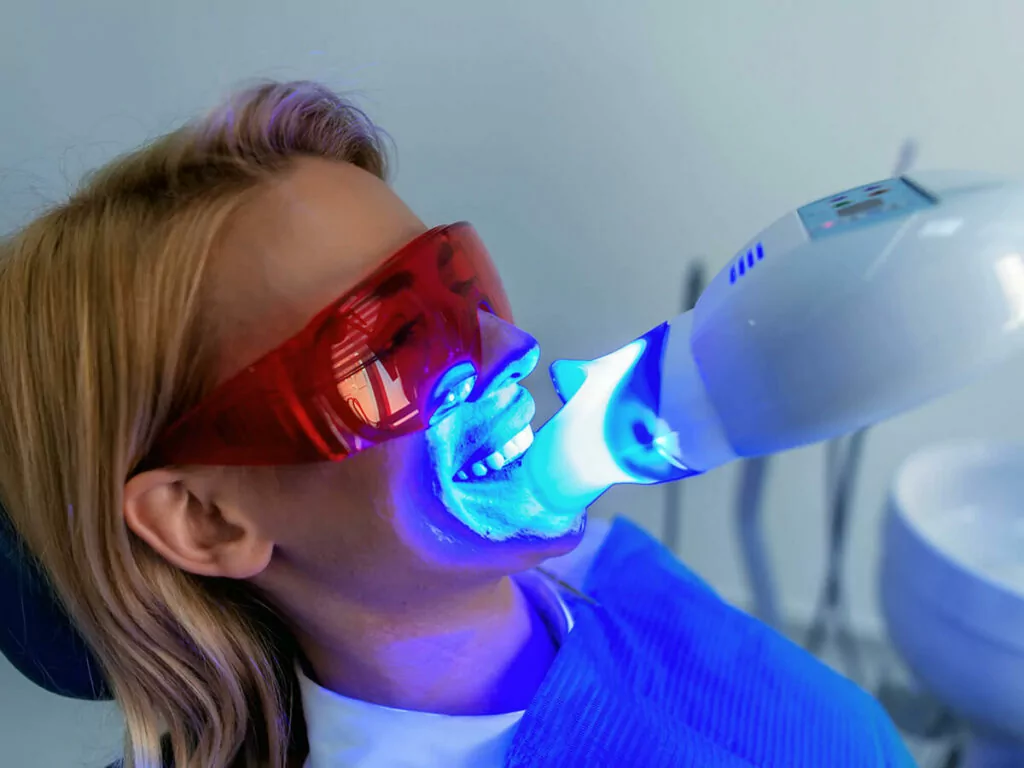 patient wearing protective glasses receiving teeth whitening via bright light