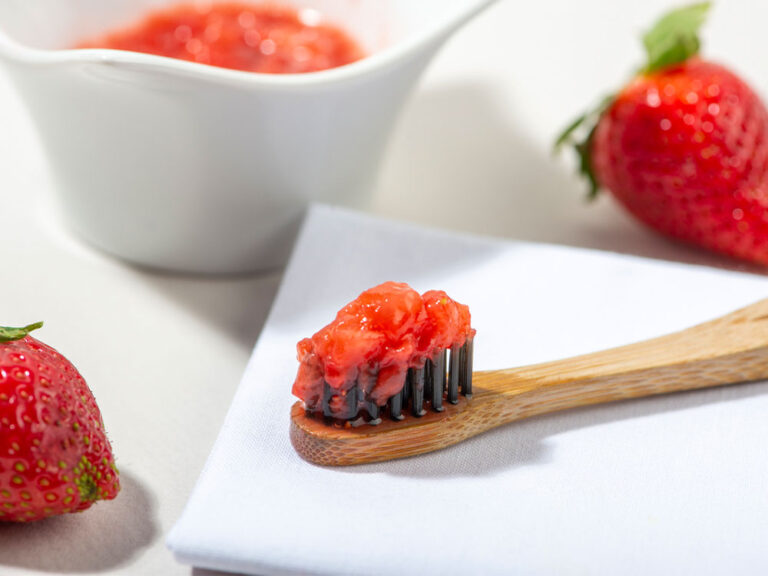Tooth brush with mashed up strawberry covering the bristles.